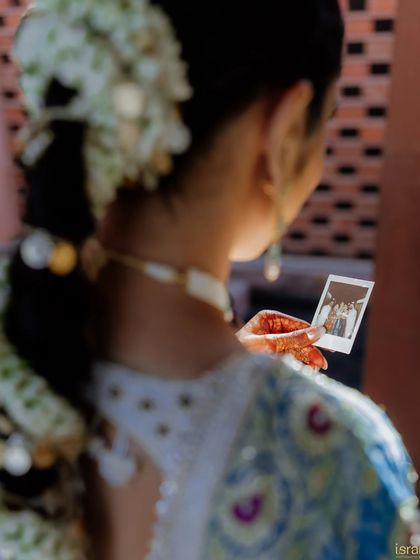 A sentimental moment as the bride looks at a polaroid of her family. We believe in incorporating personal touches that tell the couple's unique story.