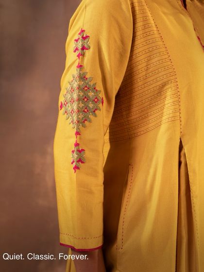 The sleeve of our yellow Ruhani kurta showcases the intricate Pakka embroidery, a craft that is quiet, classic, and forever. These timeless stitches are a hallmark of the desert artisans we work with.
