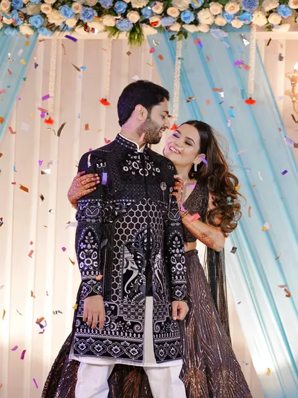 A joyful moment from the sangeet, with confetti raining down on the happy couple. Her arm around him, their smiles are infectious and full of love.