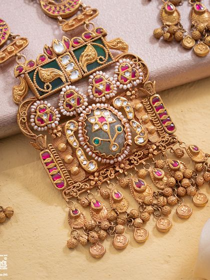 A detailed view of the Maharani Haar's central pendant. Here, you can see the masterful layering of gold, the precision of the gemstone setting, and the delicate pearl work that defines its royal character.