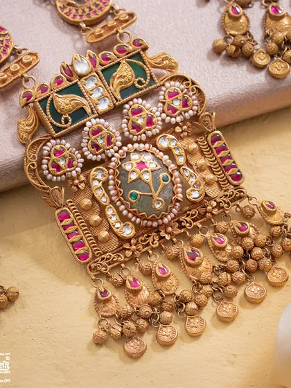 A detailed view of the Maharani Haar's central pendant. Here, you can see the masterful layering of gold, the precision of the gemstone setting, and the delicate pearl work that defines its royal character.