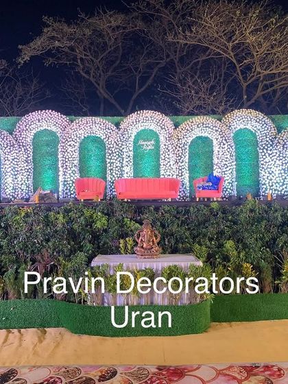 This reception stage was designed to blend with the natural surroundings. We used a series of green arches covered in white flowers, set against a backdrop of real trees, to create a beautiful and organic open-air setting.