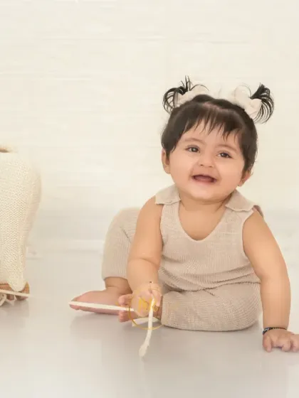 A crawling baby girl smiles as she plays with a toy elephant on wheels.