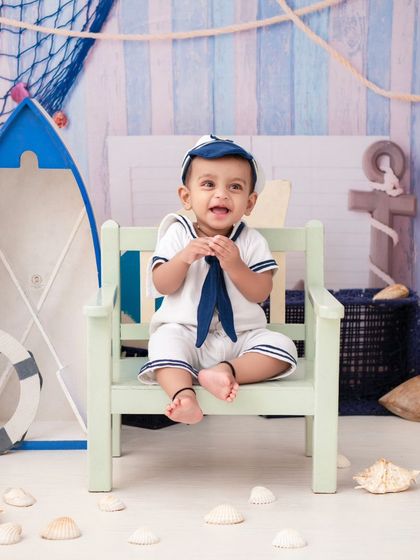 A smiling sailor sitting on a bench. The light and airy feel of this nautical set is perfect for capturing happy, classic portraits.