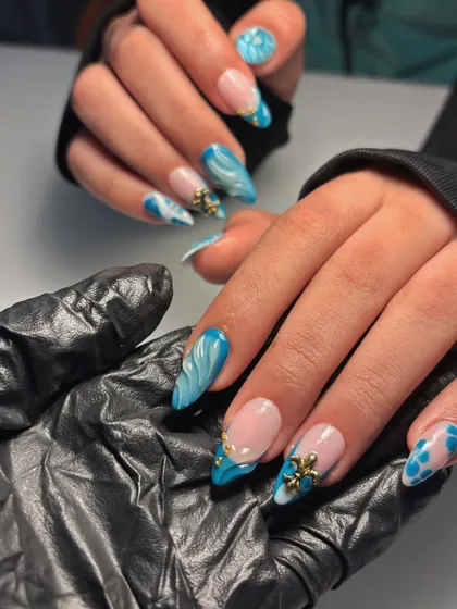 The full view of this ocean-inspired set. It features a mix of blue marble, abstract spots, and a modern French tip, all brought together with gold 3D charms.