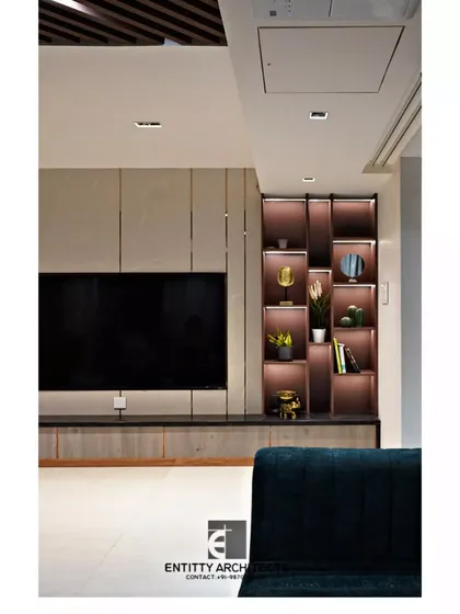 Detail is key to creating a high-end feel. This custom TV unit features a lit display niche for personal artifacts, seamlessly integrated into a larger travertine-clad wall panel for a polished, monolithic look.