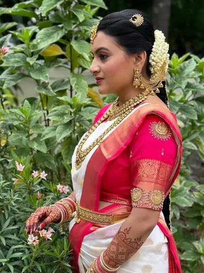 A side profile showcasing the complete bridal look. You can see the intricate details of the temple-style jhumkas and the hair accessories that perfectly complement the necklace set.