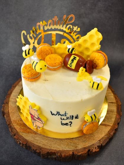 Another view of the "What will it bee?" baby shower cake, showing the arrangement of the fondant bees, honeycomb, and macarons around the cake.