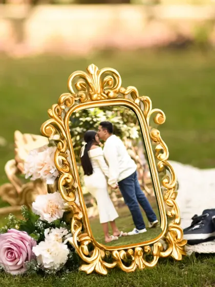 A creative way to frame your memories. This shot features a photo of the couple within an ornate golden frame, set up beautifully in a park for a unique maternity picture.