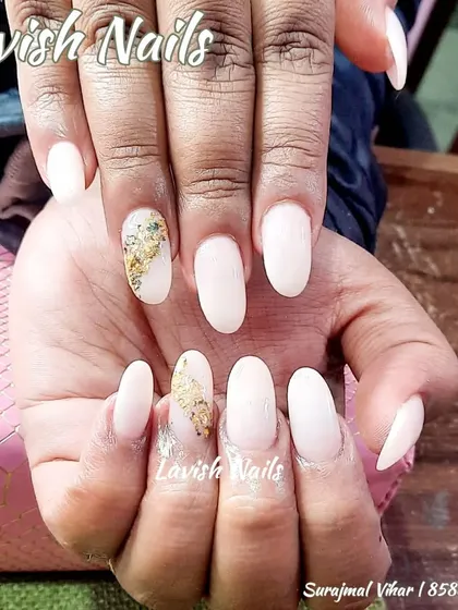 Milky white almond nails with a single accent nail featuring a touch of gold foil.