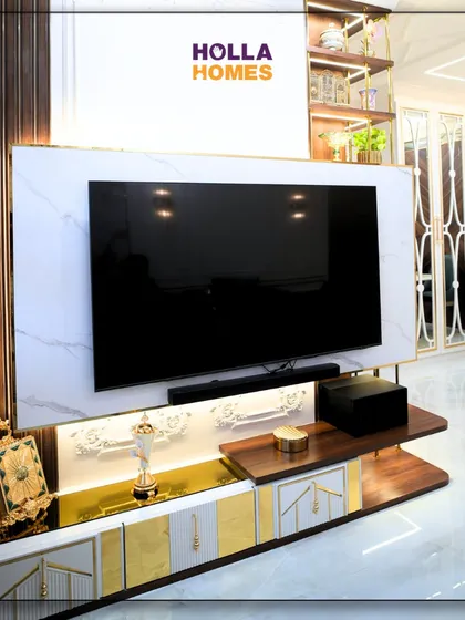 This custom-designed TV unit is the centerpiece of the Parisian living room. It combines white marble finish with wood and gold accents, offering both open shelves for display and closed cabinets for storage.
