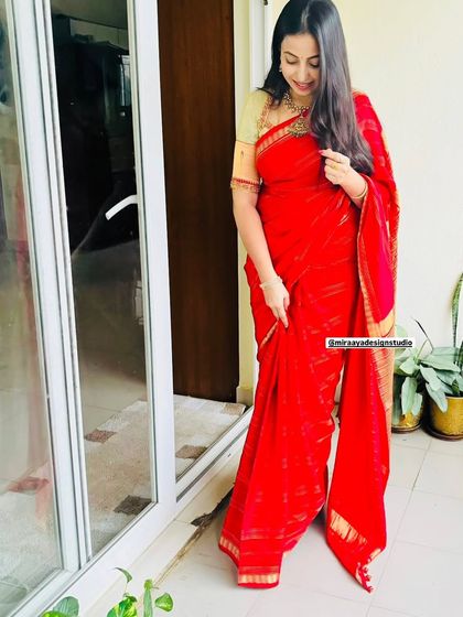 A client looking elegant in a classic red saree with a simple gold border, paired with a custom-fit blouse.