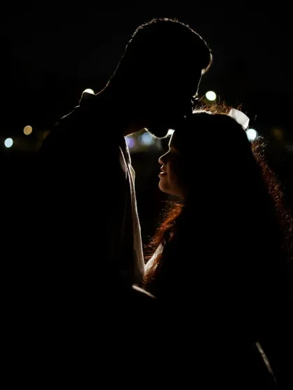 A dramatic silhouette portrait of the couple against the dark night, with a gentle forehead kiss. This technique creates a feeling of intimacy and romance.