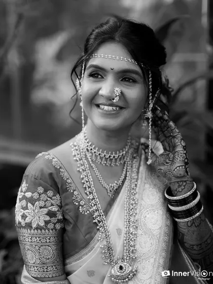 A timeless black and white bridal portrait. This image highlights the bride's joyful expression and the delicate details of her jewelry and embroidered blouse, creating a classic and elegant feel.