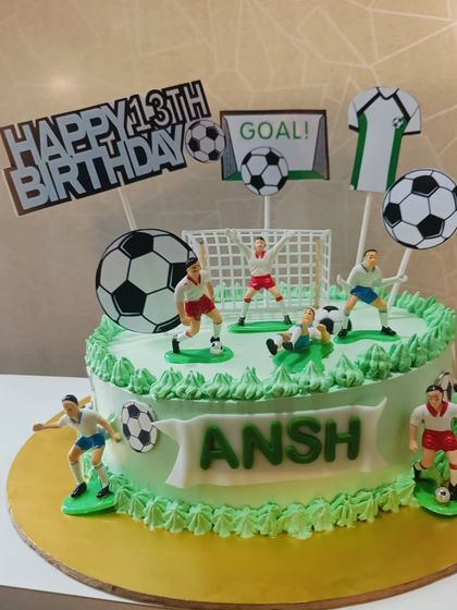 A dynamic football-themed cake for a 13th birthday. The cake is decorated with fondant players, a goal, and soccer balls to create an action-packed scene.