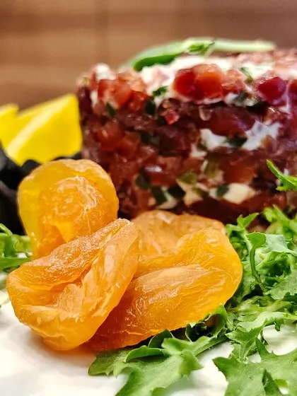 Board goals level: expert! This jewel-toned cheese creation pops with creamy layers, juicy cherry tomatoes, tangy olives, and golden dried apricots for a sweet and savory bite.