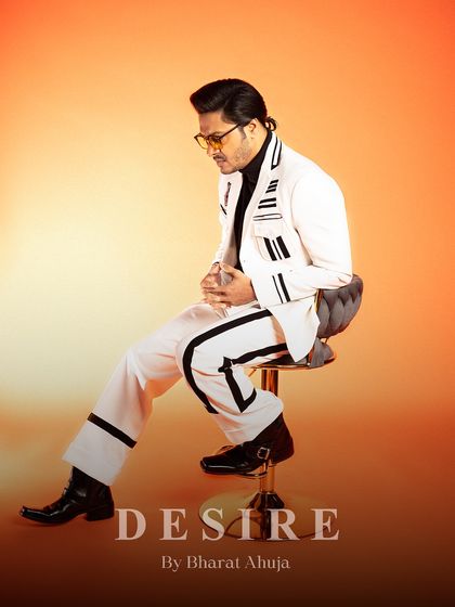 A side profile of the seated pose, highlighting the striped details on the trousers and the jacket's sharp tailoring.