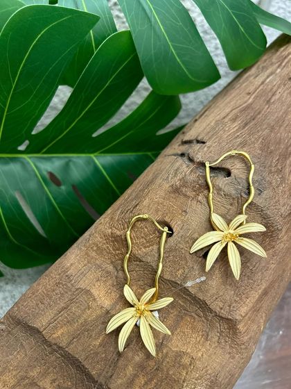 These whimsical gold drop earrings feature a delicate flower, adding a touch of playful charm to your look.
