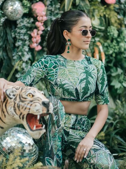 A cool and stylish shot of the bride with sunglasses, posing next to a tiger statue, perfectly fitting the jungle theme.