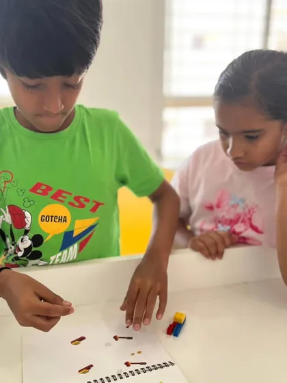 Two students collaborate on a project, following instructions from a workbook. Our programs encourage teamwork and peer-to-peer learning.