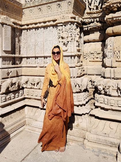 An earthy-toned traditional outfit stands against the intricate carvings of the Dwarkadhish temple, blending culture and personal style.