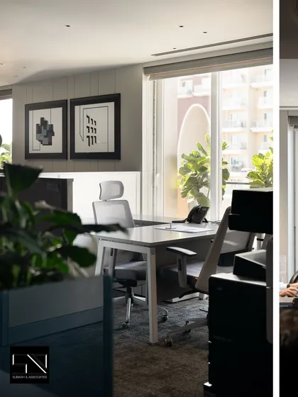 A glimpse into a private office or cabin space, where natural light floods in from a large window. The design maintains the office's overall theme of clean lines, neutral colors, and touches of greenery.