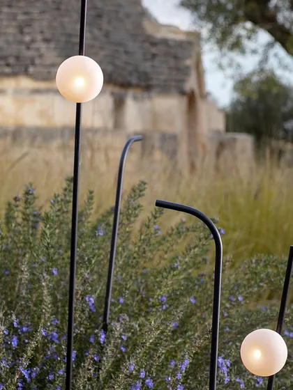A closer view of the firefly-inspired outdoor lights. The thin black stems blend into the foliage, leaving only the soft, glowing orbs visible at night.