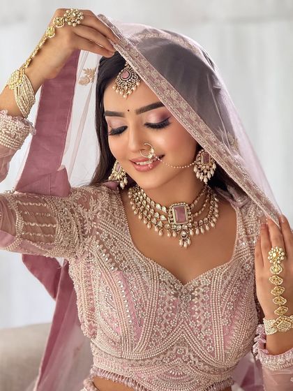 A close-up of the bride, showcasing the beautiful details of her lehenga and the soft, shimmery eye makeup.