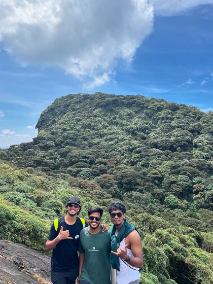 Three trekkers posing with the majestic peak in the background on the Kumara Parvatha trail.