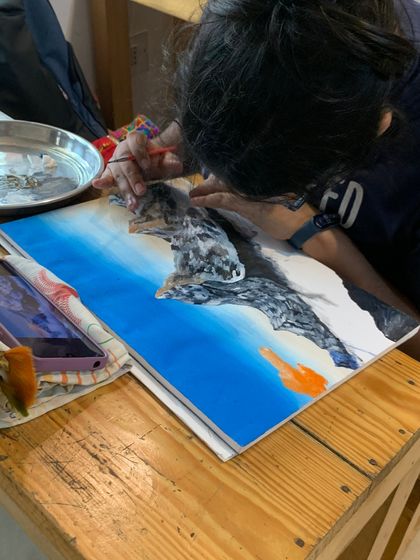 A student works on a dramatic mountain scene in watercolor. This piece demonstrates how to create strong contrast and texture, even with a fluid medium.