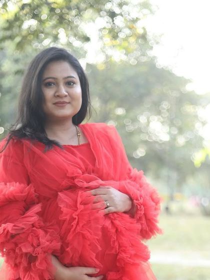 A beautiful outdoor maternity shoot. The mom-to-be looks radiant in her red gown, with soft and natural makeup that enhances her glow.