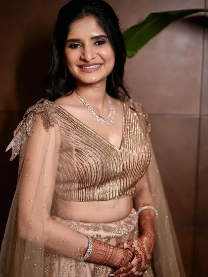 A full portrait of the bride in her stunning golden engagement lehenga. The makeup is elegant and sophisticated, a perfect match for the outfit.