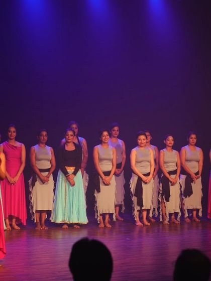 A wide shot of the performers and our founder on stage, taking a bow after a successful show.