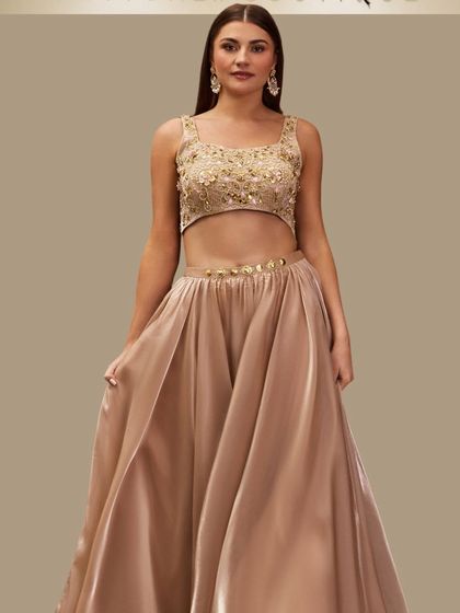 A frontal view of our champagne gold lehenga, showcasing the intricate handwork on the blouse and the luxurious sheen of the satin skirt. A truly elegant choice.