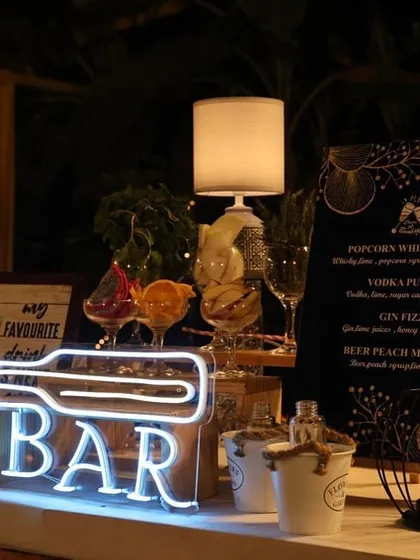 It's all in the details. This close-up shows our custom neon signage and a bespoke cocktail menu featuring creative drinks like the 'Popcorn Whisky Sour'. We work with you to design every element to fit your unique theme and taste.