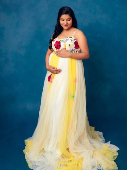 A simple yet stunning portrait of a mom-to-be in our yellow and white floral gown against a classic blue backdrop.