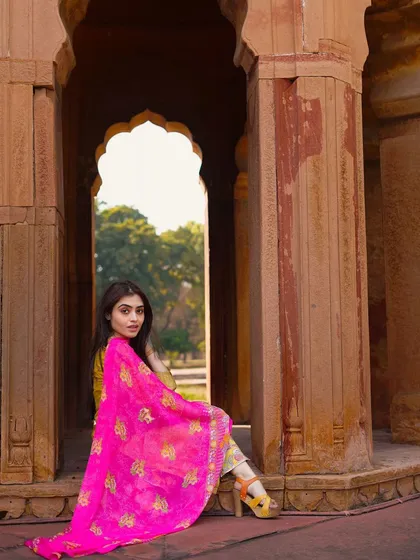 A seated pose that showcases the full sweep of the dupatta. This composition allows for a closer look at the fabric's details while maintaining an elegant and relaxed posture.