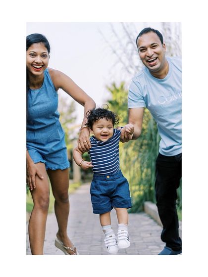 A family playing together, swinging their baby. The joy and movement are perfectly captured.
