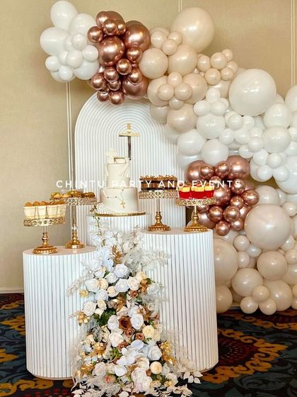 A First Holy Communion decoration with a sophisticated color palette. The setup uses white, beige, and rose gold balloons with modern ridged pedestals.