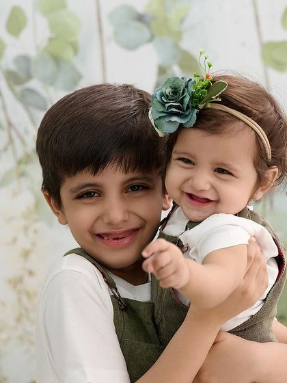 A sweet and simple portrait of a brother and his baby sister. The light, leafy background and their happy expressions make for a timeless image that celebrates their sibling bond.