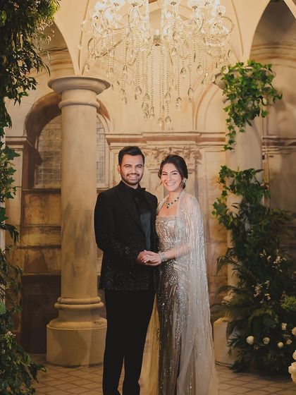A portrait of the couple, looking effortlessly elegant against a backdrop of classic architecture and lush greenery.