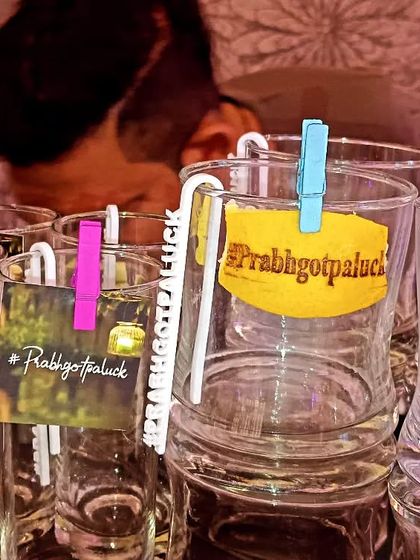 Custom glass tags with the '#Prabhgotpaluck' wedding hashtag, attached with colorful clips for a playful touch.
