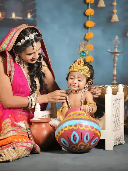 A tender moment between a mother dressed as Yashoda and her child as baby Krishna, capturing their divine bond.
