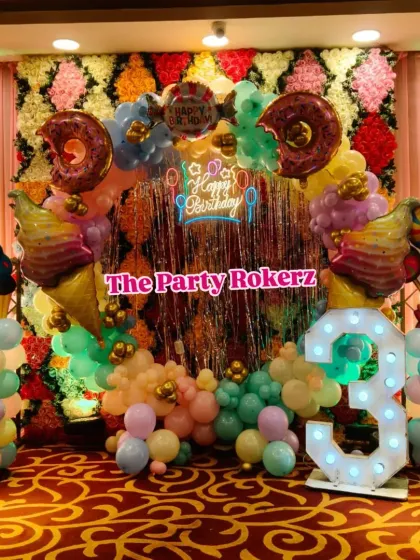 A different perspective of the Candyland birthday setup. Here you can see the mix of pastel balloons, a shiny fringe curtain, and sweet-themed props like lollipops and cupcakes.