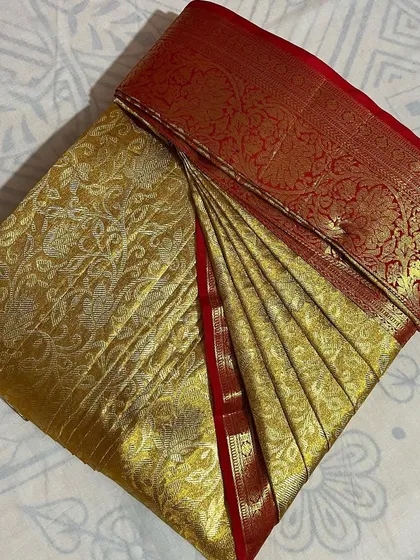 A classic gold saree with a red border, a timeless piece folded for preservation.