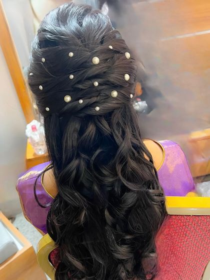 A beautiful half-updo with a braided detail and scattered pearls, perfect for a reception or engagement.