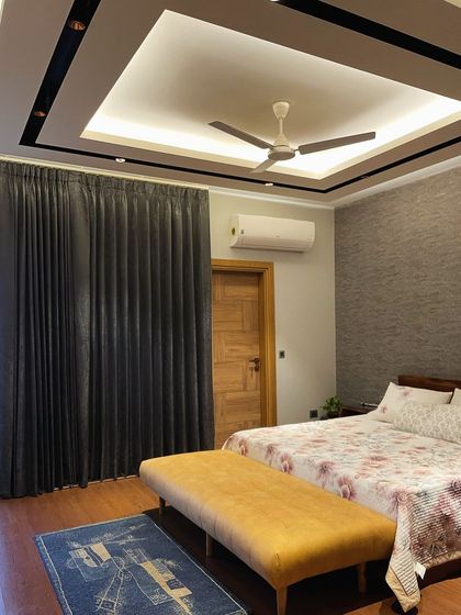 Another view of the grey and mustard bedroom, showing the dark grey curtains and the modern false ceiling design with integrated lighting.