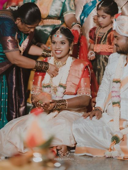 The bride being adorned with a necklace by a family member, a beautiful moment of tradition and family love.