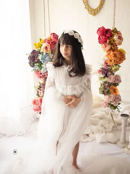 A wider view of the floral swing setup, showing how the flowers frame her and create a magical, garden-like atmosphere.