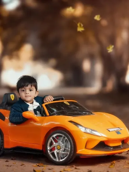 Cruising in style. This little boy looks like a pro in his orange sports car, enjoying an autumn drive through the woods.